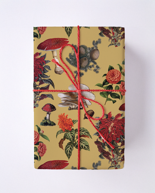 Yellow wrapping paper with red mushrooms and floral motifs tied with red string.